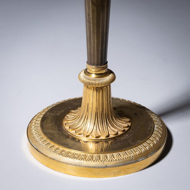 A pair of elegant Empire candlesticks crafted from partially fire-gilded bronze, dating to the early 19th century. Each...