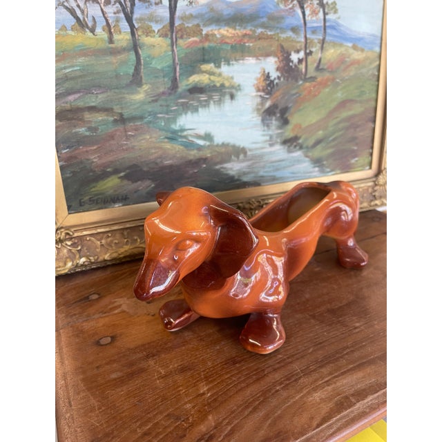 This vintage Hull Pottery dachshund planter features a sleek mid-century design with a warm brown-to-orange glaze,...