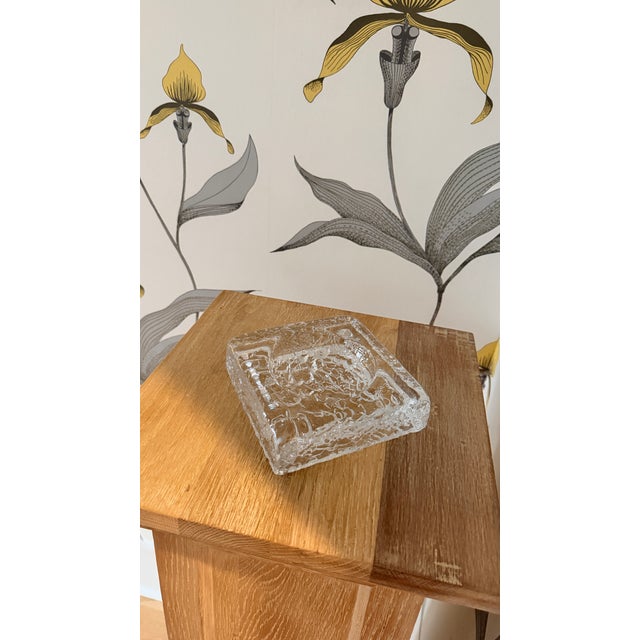 A substantial square ashtray in thick, textured crystal by Orrefors, Sweden's legendary glassworks. The surface features...