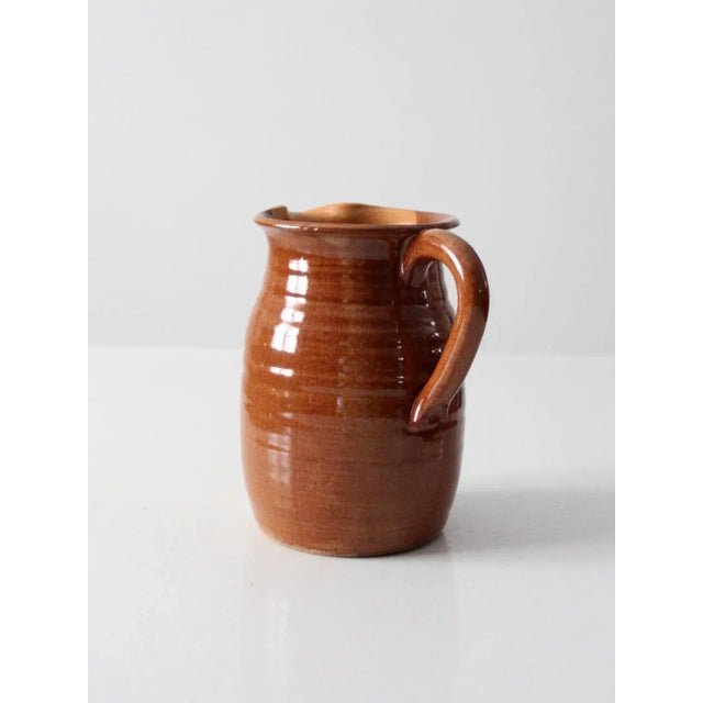 This is a vintage studio pottery pitcher. Signed by the artist, Wilhelm, the hand-crafted vase features a two tone glaze...