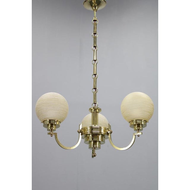 A refined art deco brass chandelier produced in czechoslovakia in the 1930s, showcasing the distinctive craftsmanship of...