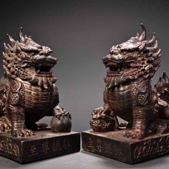 This is a matching pair of cast bronze guardian lion (Pixiu) figurines, featuring a gilded finish with a dark, aged...