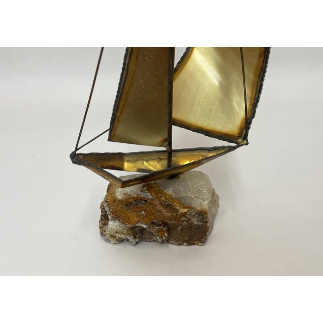 A striking vintage mid-century modern sailboat sculpture featuring gracefully curved brass-toned metal sails, delicate...