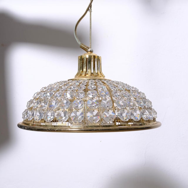 Pendant light, featuring a brass dome structure decorated with numerous faceted crystal gems. Inside, another beautiful...