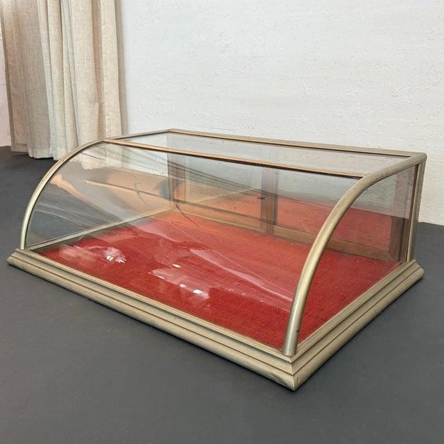 This antique early 20th century table top display case features a nickel-plated wood frame, curved glass front and mirror-...