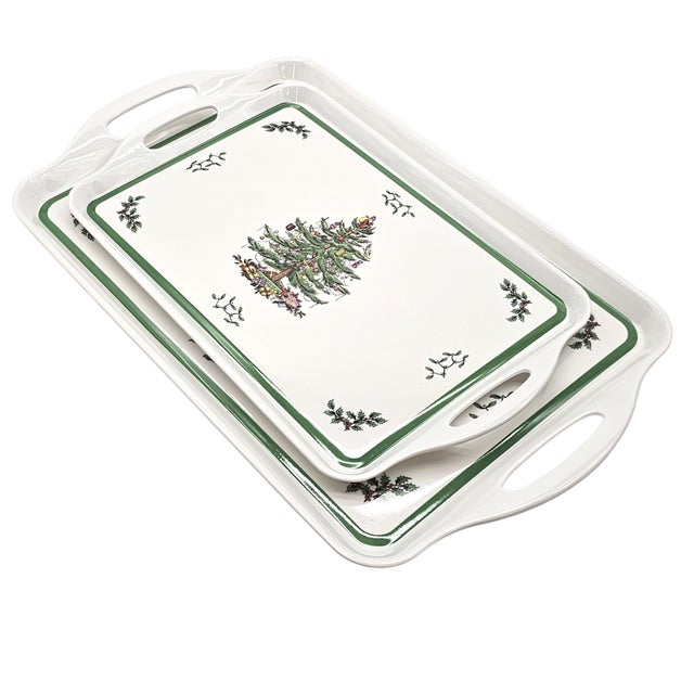 Holiday trays, white and strong, framed in green with holly scattered like whispers of December. At the center, a...