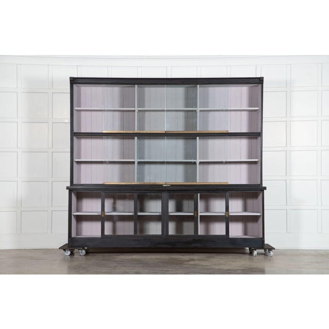 Circa 1900 monumental ebonized glazed mahogany & pine haberdashery cabinet with 9 glazed sliding doors. Measures : w249 x...