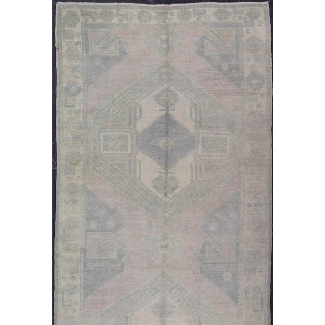 This Turkish Oushak carpet features a design with two central medallions, as well as patterns of smaller all-over diamonds...