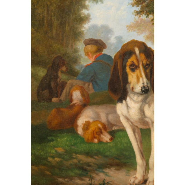 A Belgian signed Joost-Vincent De Vos oil on canvas dog painting from the 19th century depicting hounds and a young boy...