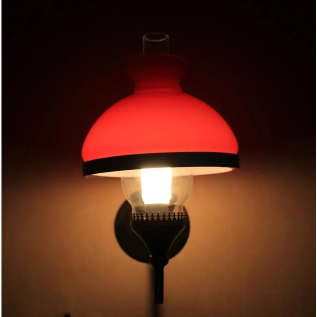 French pair of wall sconces. Red opaline lamp shades. Forged iron. Dimensions: Height 11" / 28 cm Width 6.2" / 16 cm Depth...