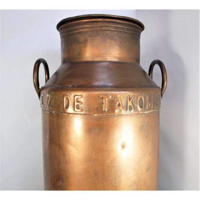 A large antique copper milk pail from Holland. Front has the farm name, “C Z De Takoms” and back has number “7658”. Pail...
