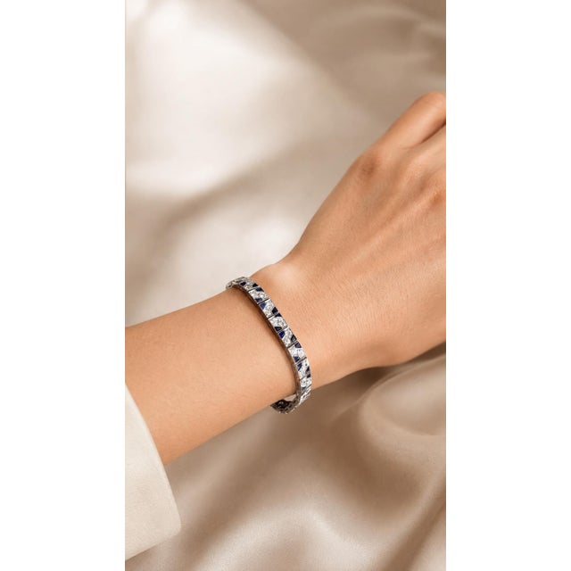 An elegant platinum bracelet featuring a geometric mosaic of diamonds and sapphires. Each articulated rectangular link...