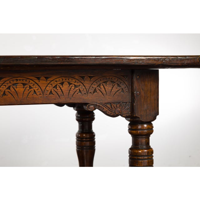 An English oak table from the 19th century with carved apron, turned legs and H-Form cross stretcher. An English oak table...