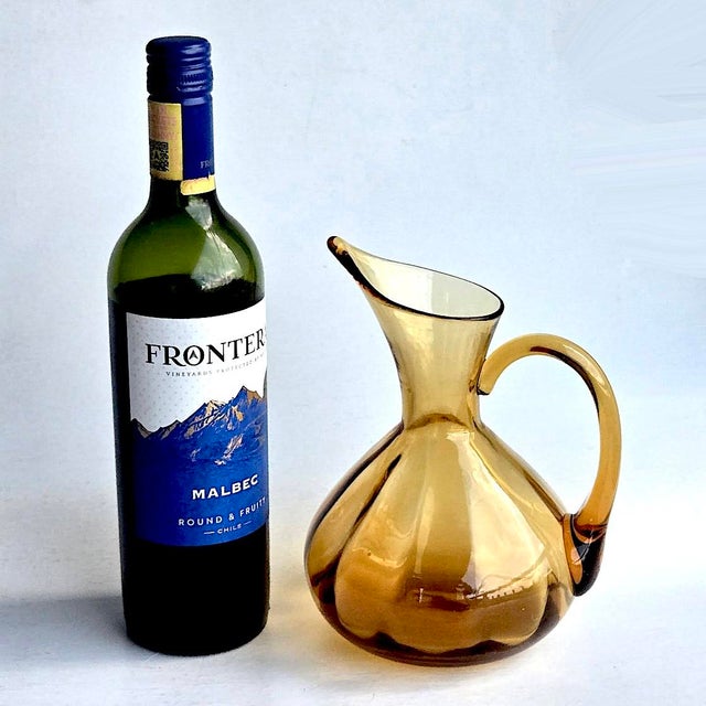 Offered is a vintage hand-blown Rainbow Glass optical ribbed pitcher in amber. It has an applied handle and an unpolished...