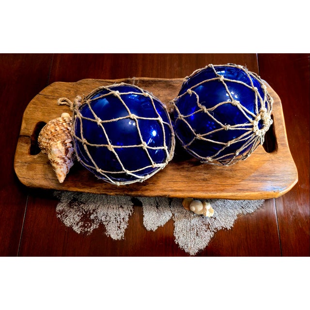 A pair of hand-blown cobalt blue glass fishing floats in original jute nets, 8 inches diameter (approx. 9" including the...