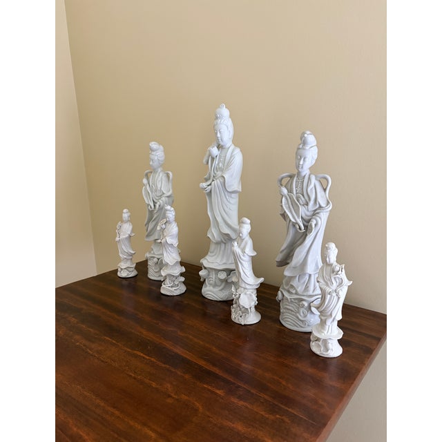 A serene grouping of seven blanc de chine figures depicting Quan Yin, the bodhisattva of compassion, rendered in softly...