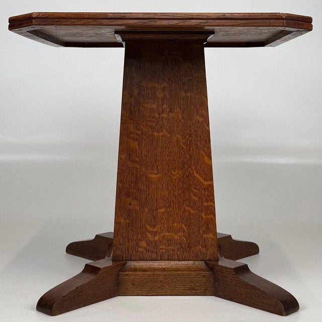 A charming early 20th-century English side table, finely crafted from oak and distinguished by its substantial square-form...