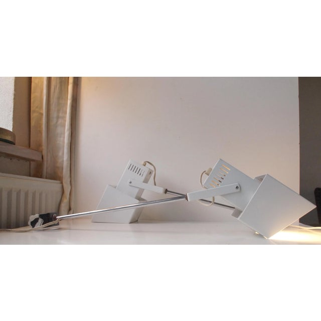 A pair of white and chromed metal long adjustable wall lights with screw-on mounts that can be fastened to shelves or...