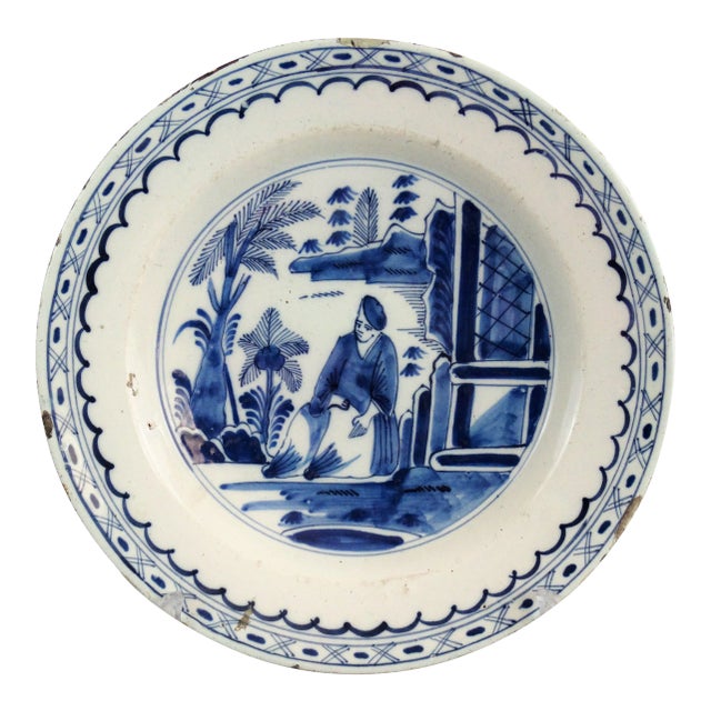 An 18th-Century English Delft chinoiserie charger with a figure in a landscape with trees, a building, and water. It is...