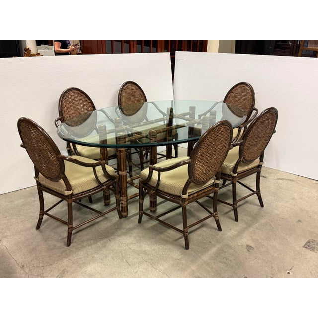 Design Plus Gallery presents a Vintage McGuire Furniture Dining Set. The table has a beveled oval glass top set over an...