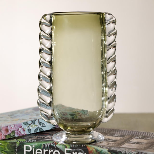 The Vintage Braided Glass Vase is a sculptural decorative accent defined by its raised braided detailing and timeless...