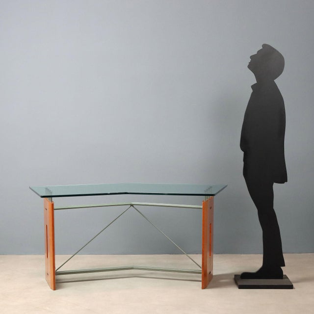 Desk with base in Tanganyika walnut veneer and metal, transparent glass top. This piece is attributed to the mentioned...