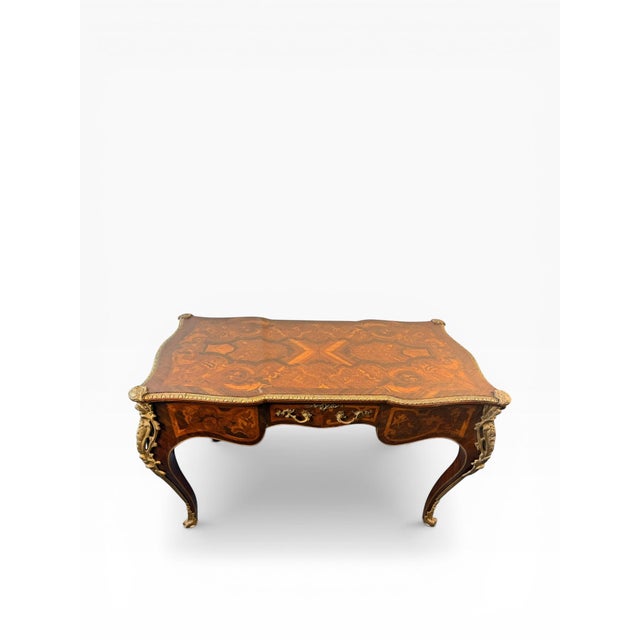 A beautifully crafted French-style writing desk featuring rich marquetry inlay and ornate gilt bronze (ormolu) mounts. The...