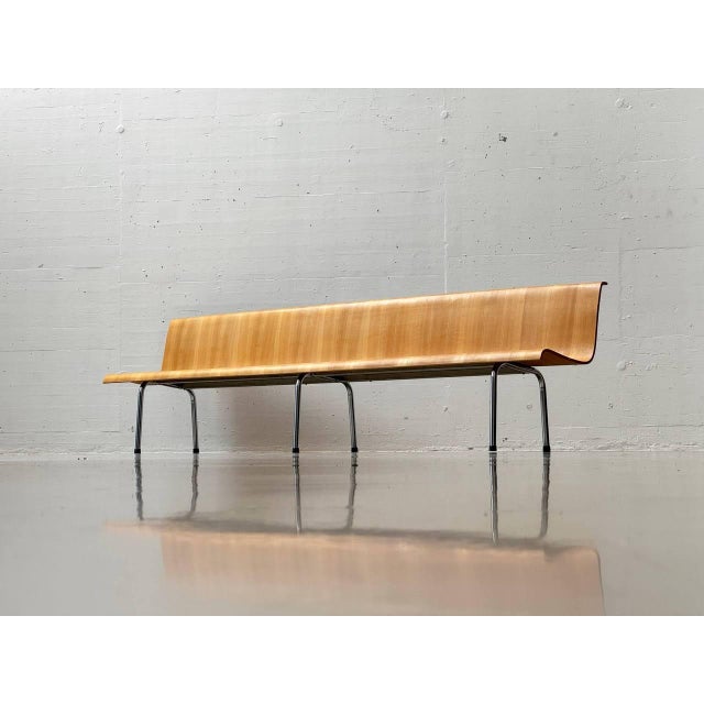 A sculptural wooden bench with elegantly curved lines, crafted from molded beech plywood. The continuous seat and backrest...