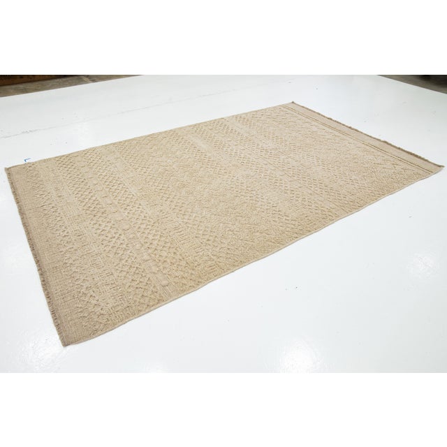 This Modern hand-loom wool rug showcases a stunning beige-taupe field with an all-over geometric design. This rug measures...