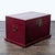 This wooden trunk features a deep red finish and metal hardware. It has a hinged lid and sturdy side handles for easy...