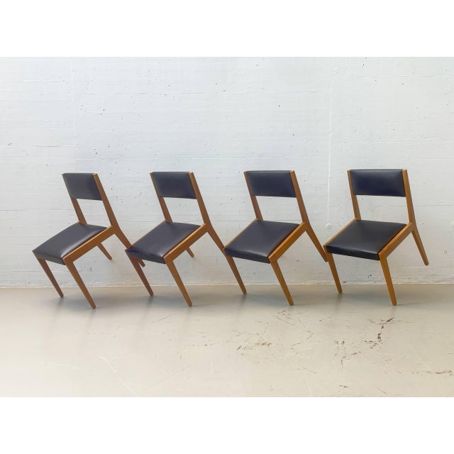 These vintage dining chairs date back to the 1960s and combine a clean, modern wooden frame with black upholstery. The...