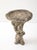 An English mid-20th-century composite stone birdbath, with a textured, hollowed-out log basin, rests atop a pedestal...