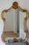 Rococo vintage gold gilt wall mirror. It has a beautiful hour glass shape, with ornate c-scrolls, acanthus leaves and a...