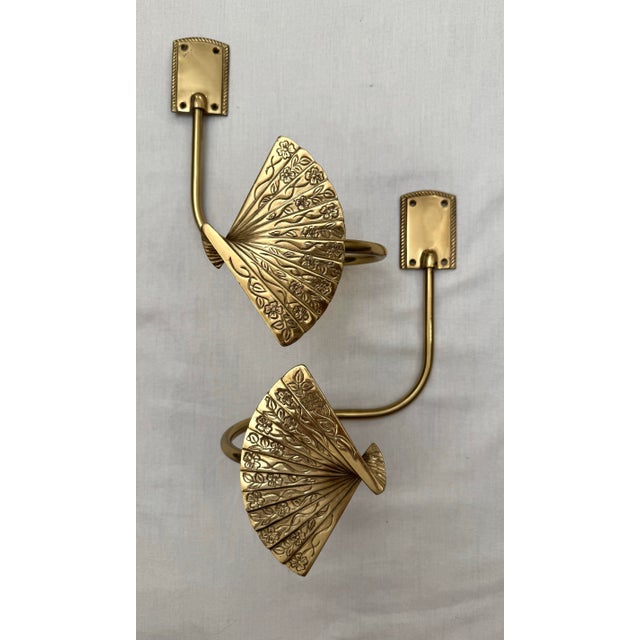 This pair of Hollywood Regency style drapery tie backs feature a singular curved arm with a three dimensional , intricate...