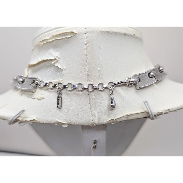 1970s rhodium plated articulated with buckle center necklace with hook clasp. Marked "MONET©" on one side of the hangtag...