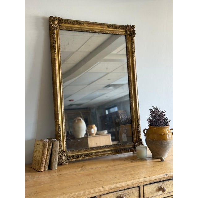 A large 19th century Napoleon III mirror with a richly detailed giltwood frame, featuring deeply carved scrollwork, floral...