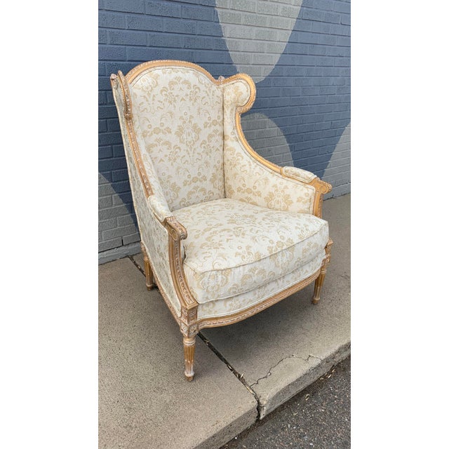 A stunning French Heritage arm chair with a textured brocade fabric and muted gold frame. Measurements: 44" high, 33"...