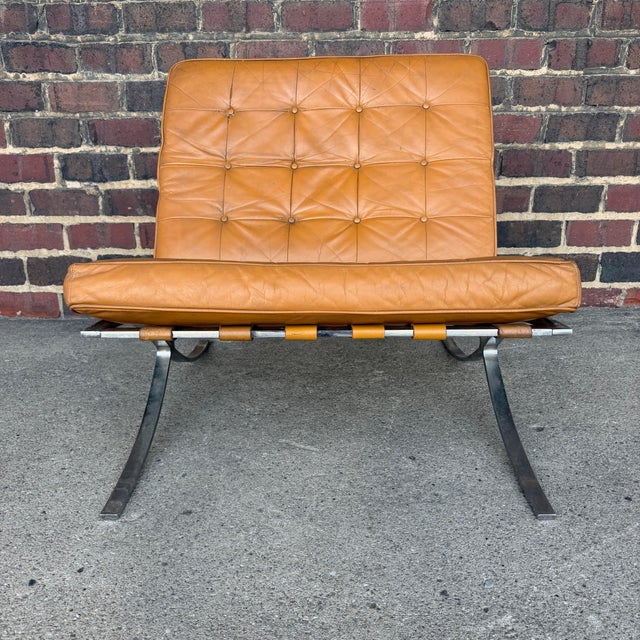 This is a tan leather and chrome Barcelona style lounge chair. It features tan button-tufted leather cushions and matching...
