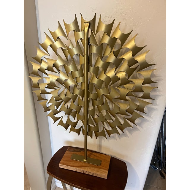 This is a a brutalist-style, multi-layered metal starburst art piece featuring interlocking gold-finished geometric metal...
