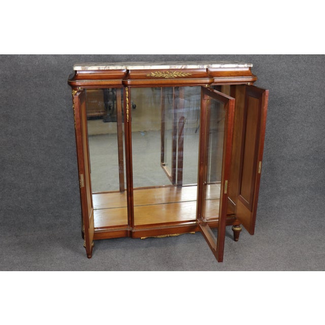 This exceptional French bronze-mounted vitrine cabinet, crowned with a richly veined (often referred to as Brèche de...