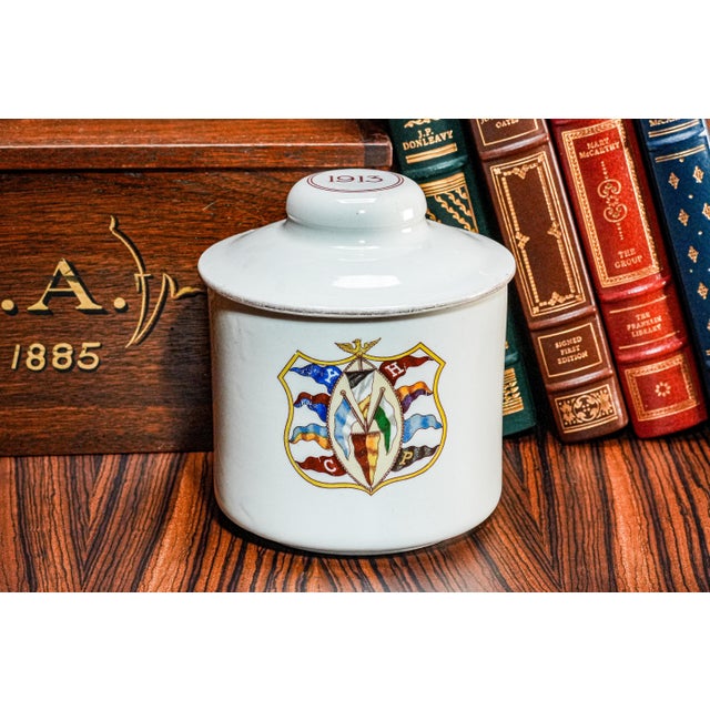 Transport yourself back in time with this antique Ivy League theme white porcelain tobacco jar, a captivating relic from...