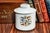 Transport yourself back in time with this antique Ivy League theme white porcelain tobacco jar, a captivating relic from...