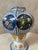An elegant earthenware vase with a rounded body, resting on an octagonal base. Its decoration combines blue and white...
