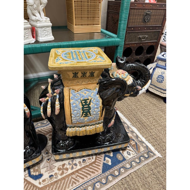 Handsome pair of elephant garden stools in an unusual color combination. The glossy black glaze sets off the other colors...