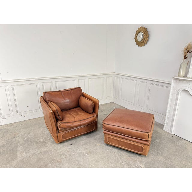 Beautiful cognac leather club chair and matching ottoman (or pouf) by Roche Bobois, dating from the 1980s. The fine...