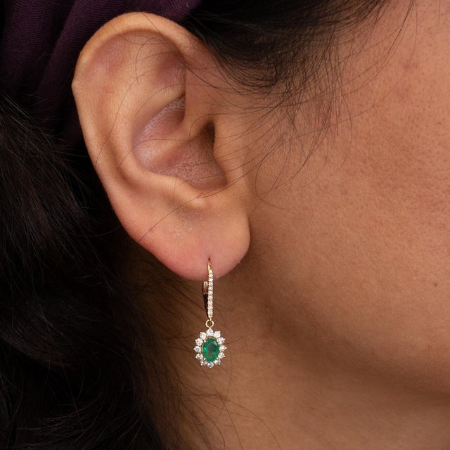 Zambian emerald earrings featuring vibrant 6x4mm gemstones, accented with natural diamonds for added brilliance. Crafted...