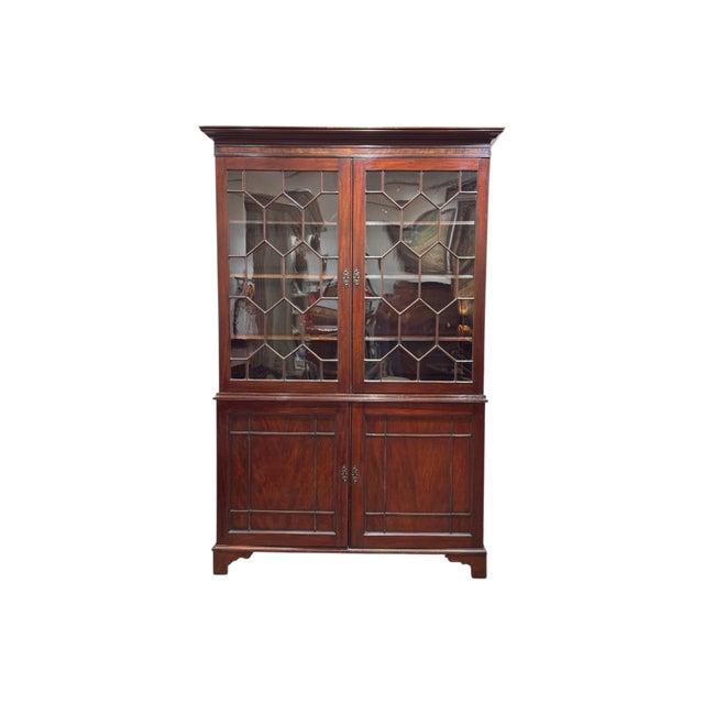 A large and impressive early 19th century English two-part bookcase with a dentil-molded cornice above a pair of astragal-...