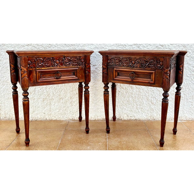 Elegant pair of Spanish nightstands crafted from solid oak. Richly carved with scrolling foliate motifs across the frieze,...