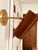 A beautifully sculptural mid-century modern wall sconce featuring a warm teak wood cylindrical shade and satin brass...