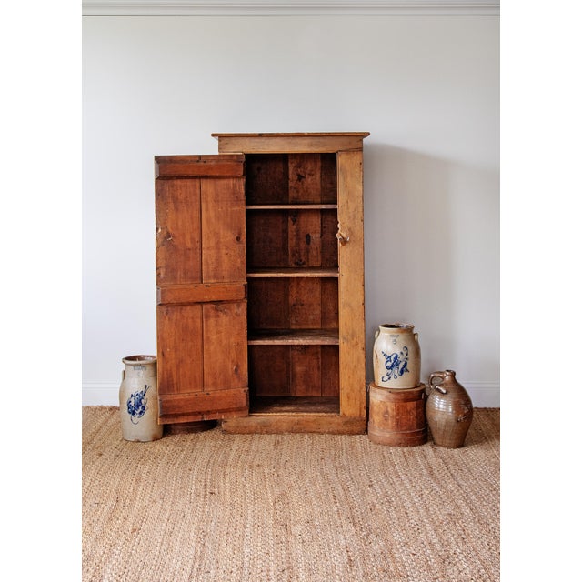 A beautifully simple antique English pine cupboard featuring a tall narrow form, warm timeworn patina, and honest...
